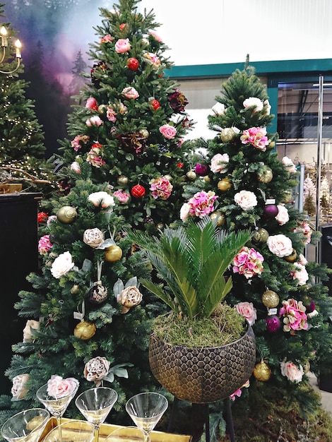 Christmas trees decorated with artificial flowers garlands and Christmas baubles