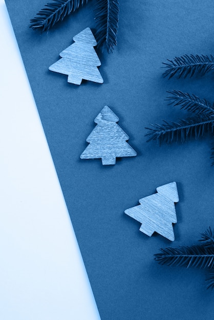 Рождественские елки и ветви дерева на голубой предпосылке. Концепция рождества, партии, праздника и торжества для открытки или приглашения. вид сверху. Классический синий цвет года 202