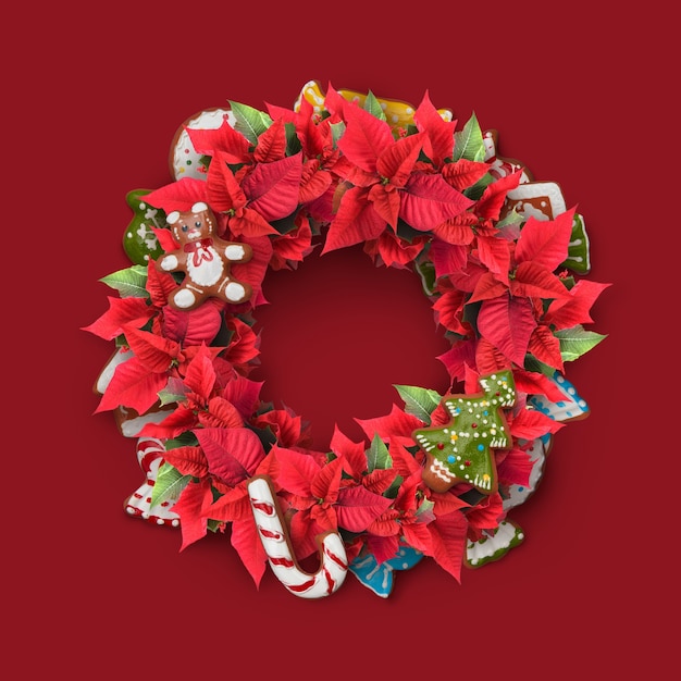 Christmas twig wreath is decorated with candy, red flowers, cookies and green leaves.