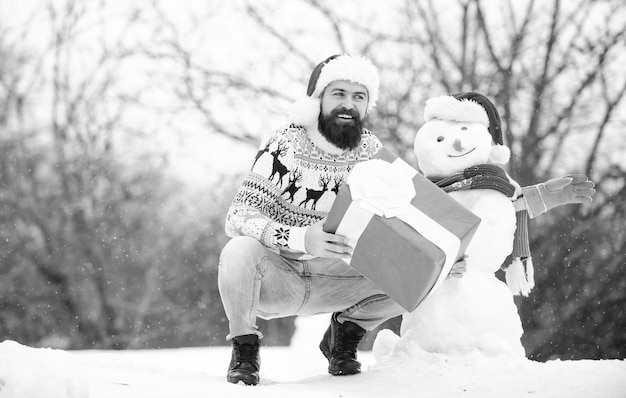 Christmas vacation man give present outdoor happy hipster ready\
for xmas bearded man build snowman happy new year winter holiday\
warm sweater in cold weather winter season merry christmas