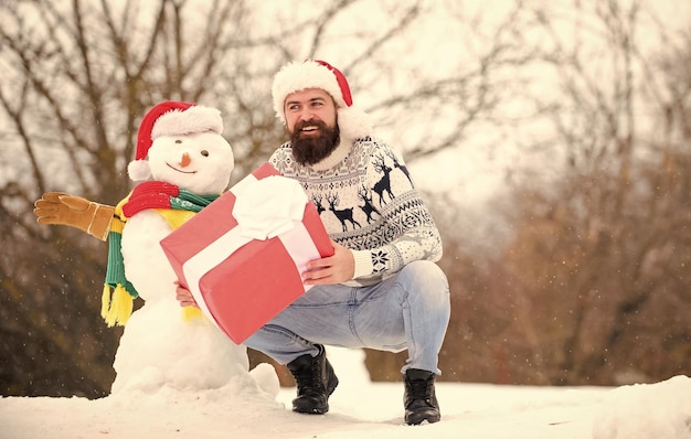 Christmas vacation man give present outdoor happy hipster ready
for xmas bearded man build snowman happy new year winter holiday
warm sweater in cold weather winter season merry christmas