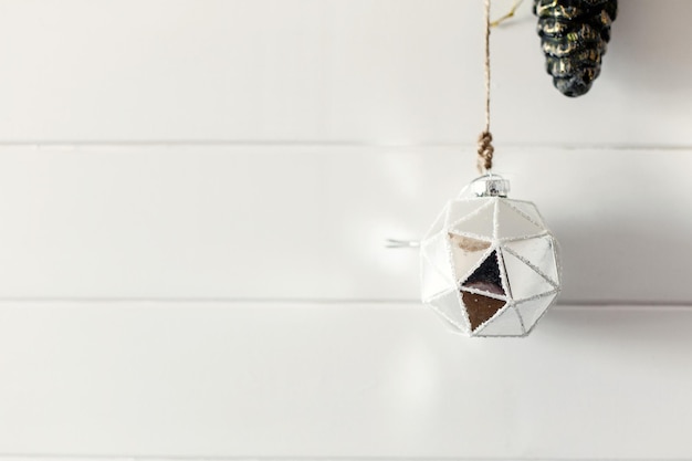 Christmas vintage bauble hanging on background of white wall in modern room scandinavian minimal style Stylish glass ornament holiday decorations Space for text