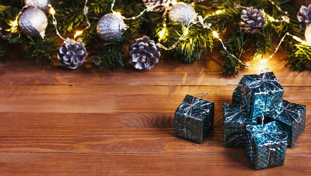 사진 나무 테이블에 빛의 화환으로 장식 된 크리스마스 벽 선물과 크리스마스 트리