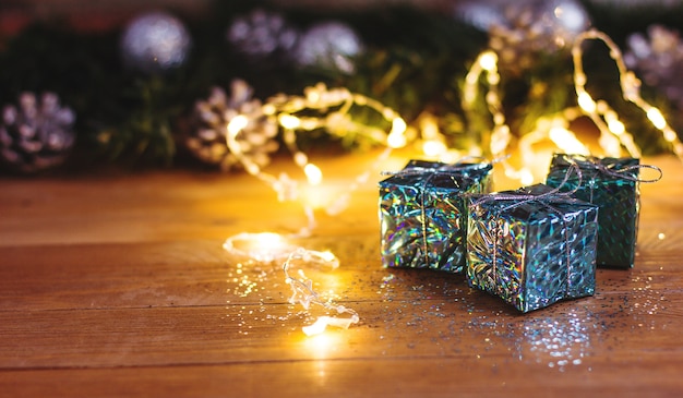 사진 나무 테이블에 빛의 화환으로 장식 된 크리스마스 벽 선물과 크리스마스 트리