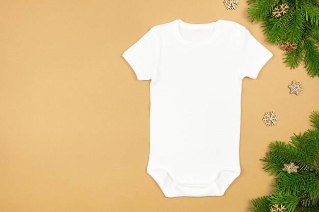 Christmas white baby girl or boy bodysuit mockup flat lay with xmas tree branches and snowflakes decoration on paper background Design onesie template print presentation mock up Top view