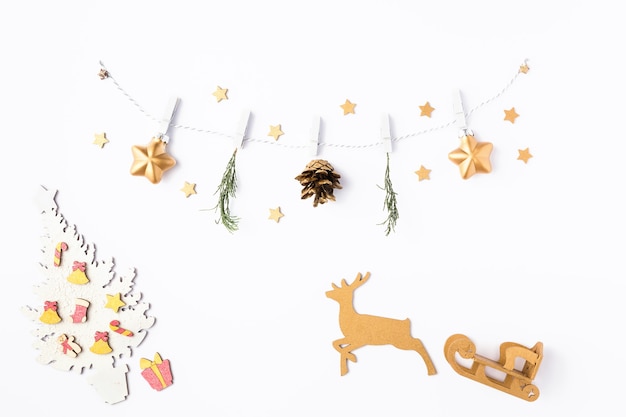 Christmas white background. Garland made of gold stars and fir tree branches. DIY composition, winter and 2020 new year concept. Flat lay, top view