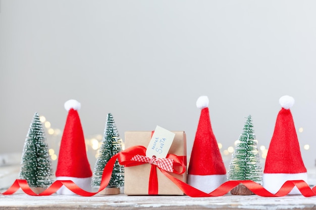 Christmas white box or present with red ribbon from Secret Danta with santa hat and xmas trees Happy holiday concept