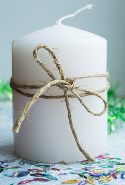 Christmas white candle tied with twine and green tinsel sequins