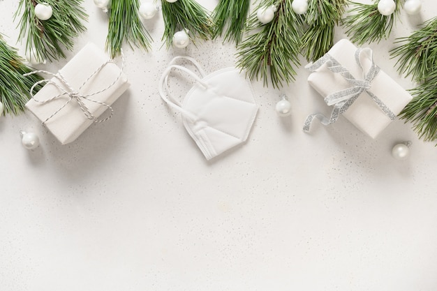 Фото Рождественские белые подарки и украшения с медицинской маской и вечнозелеными ветками