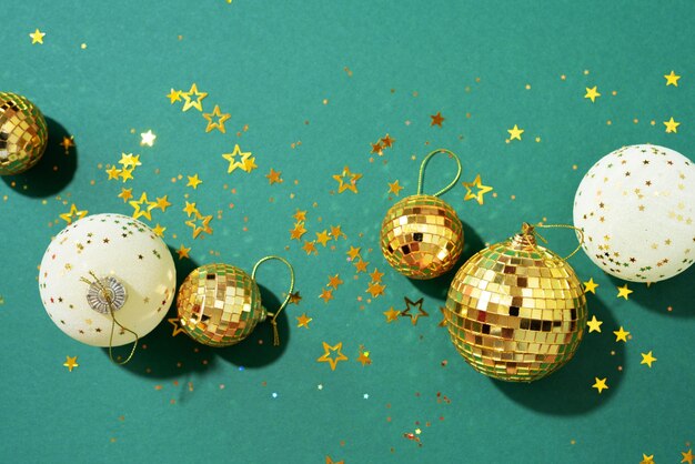 Christmas white and gold decorations mirror disco balls star sparkles over green background Flat lay top view Minimal New year party concept Christmas greeting card with copy space