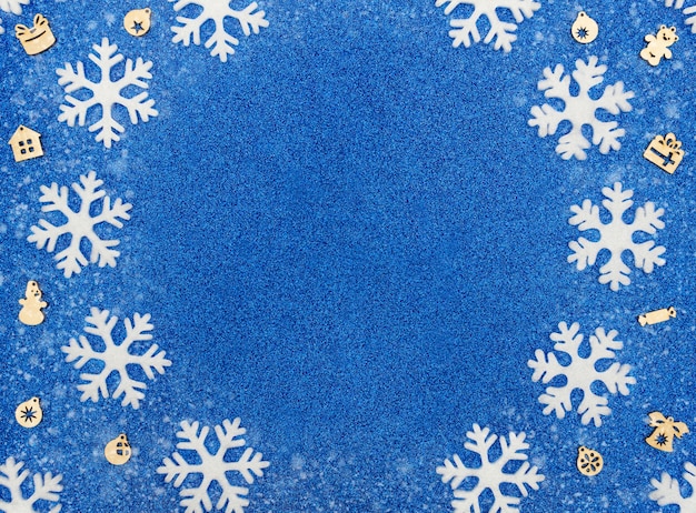 Sfondo blu natale o inverno con fiocchi di neve bianchi e decorazioni in legno