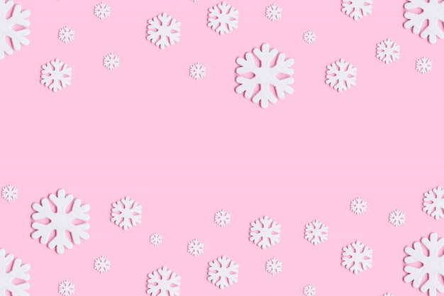 Christmas or winter composition. Pattern made of snowflakes on pastel pink background.