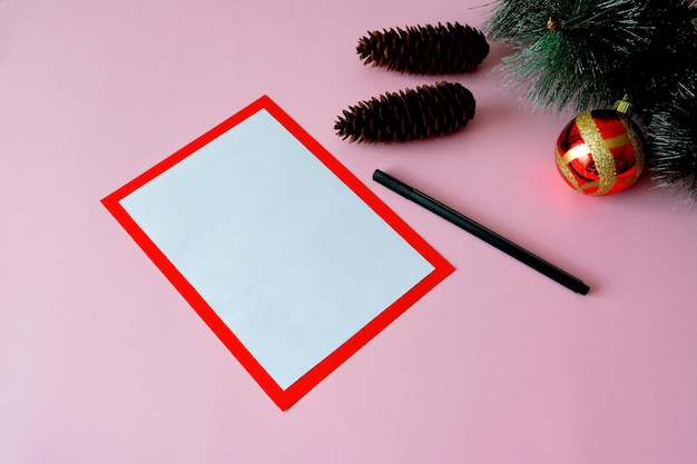 christmas wish list with black pen, pine branch and cones, close-up