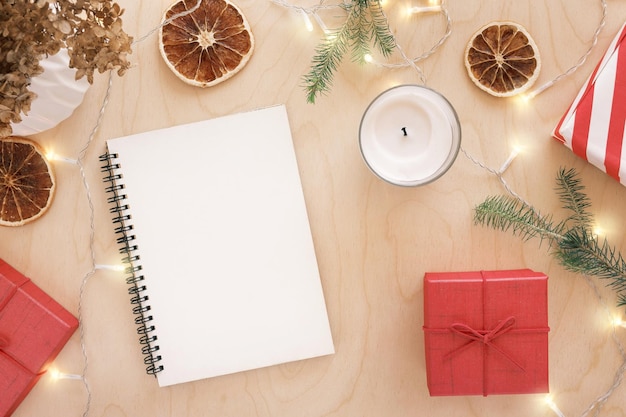 Christmas wish list writing Woman creating present list for winter holidays Top view flat lay Preparing for Xmas and New Year concept Female hand writing in empty notebook on wooden table