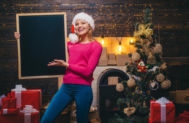 テキスト黒板コピースペースクリスマスと新年のコンセプトのための黒い机を持っているクリスマスの女性...