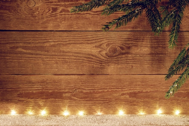 Christmas wooden background. Christmas background with garlands and a branch of a fir tree