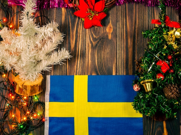 Christmas wooden background with decorations and the flag of Sweden.