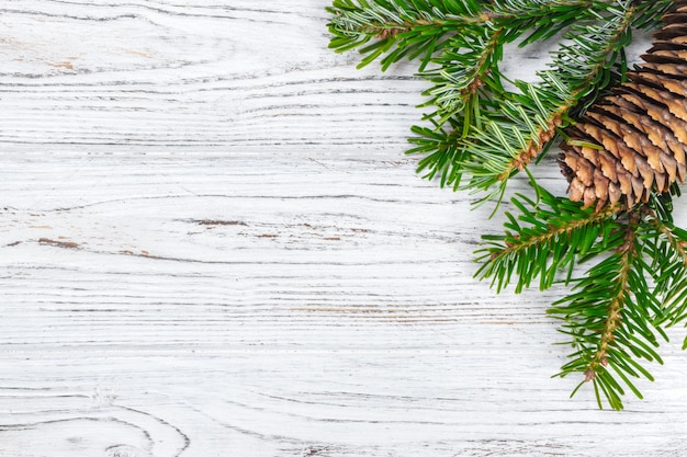 Christmas wooden background with fir tree and pine cone. Top view, copy space. 