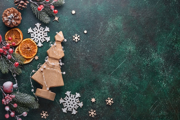 Рождественская деревянная декоративная елка с гирляндой, рождественскими шарами, подарочной коробкой, деревянными снежинками и звездами на зеленом бетонном каменном фоне для ваших рождественских поздравлений. вид сверху. рождественская открытка.