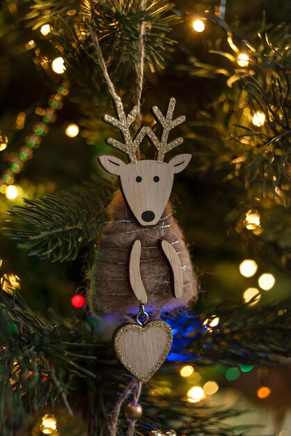 Christmas wooden deer, handmade, on the background of a Christmas tree decorated with lights of garl