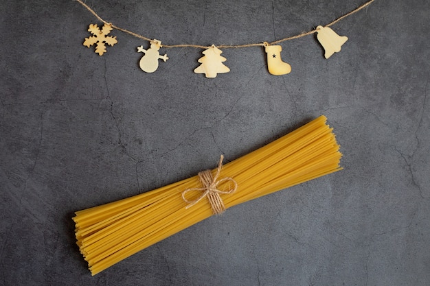 Christmas wooden figures on a rope and dry pasta on a dark background Concept holidays Christmas