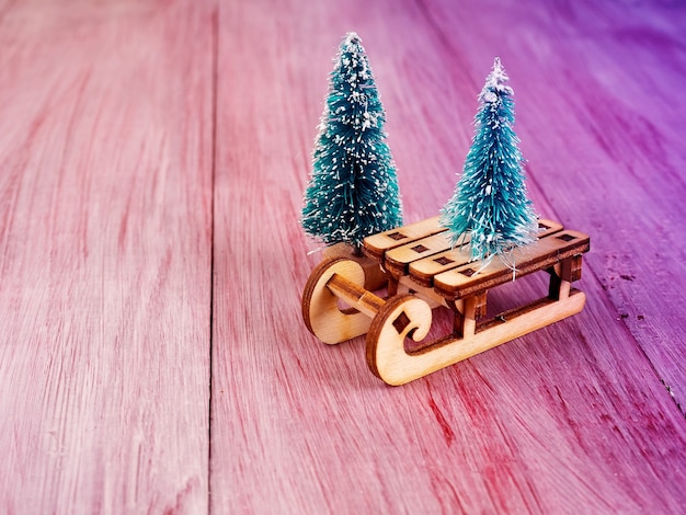 Christmas wooden toy sleigh and small Christmas tree nearby, Christmas concept, minimalism, place for text.