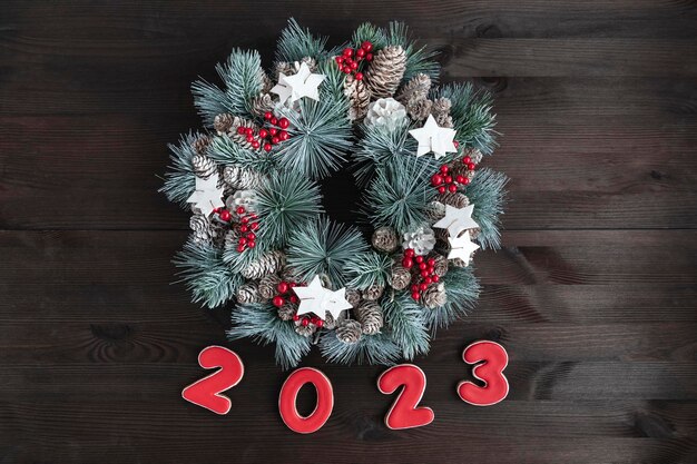 Фото Рождественский венок и надпись 2023 года из имбирных пряников на деревянном фоне новогодняя концепция