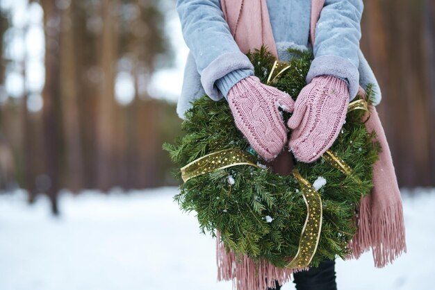 Christmas wreath in beautiful woman hands in snow forest seasonal holidays adorning. Christmas