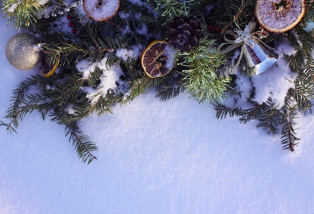 白い雪の背景にドライオレンジスライスとカラフルなボールで飾られたクリスマスリース。