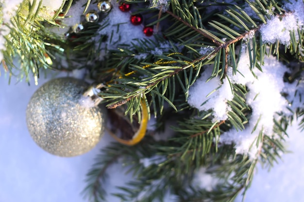 白い雪の背景にドライオレンジスライスとカラフルなボールで飾られたクリスマスリース。