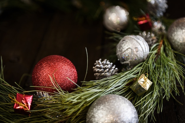 Рождественский венок из еловых веток с елочными украшениями, сосновыми шишками и подарками на коричневом фоне