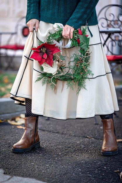 Christmas wreath in the hands of a stylish woman city walk