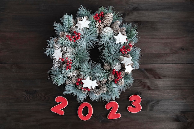 Christmas wreath and the inscription in 2023 of gingerbread on wooden background New Year concept