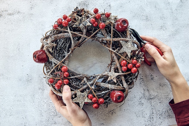 Christmas Wreath Made of branches decorated with gold wooden stars and red berry bubbles. Creative diy craft hobby. Making handmade christmas decorations.