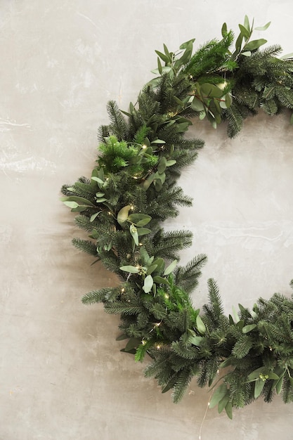 Christmas wreath made of fir branches hanging on a gray wall Half wreath