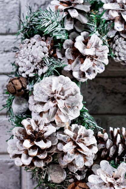 Christmas wreath made of fir branches and natural cones against
the background of a gray brick wall new year and winter holidays
christmas decor closeup