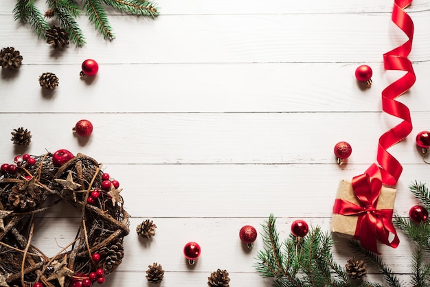 크리스마스 화환 장난감 솔방울 선물 상자 가문비나무 가지가 흰색 나무 테이블 1에 놓여 있습니다.