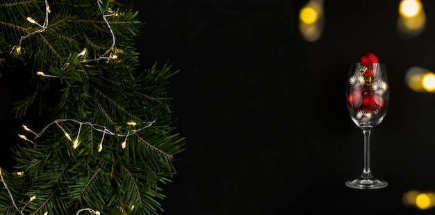 Рождественский венок и бокал с цветными бусинами на черном фоне Баннер Копией пространства