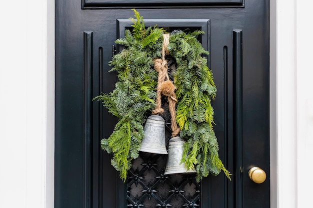 Christmas wreath with bells on entrance vintage black door outside. Veranda front door decorated by christmas festive wreath decor. Traditional Christmas outdoor exterior in Netherlands