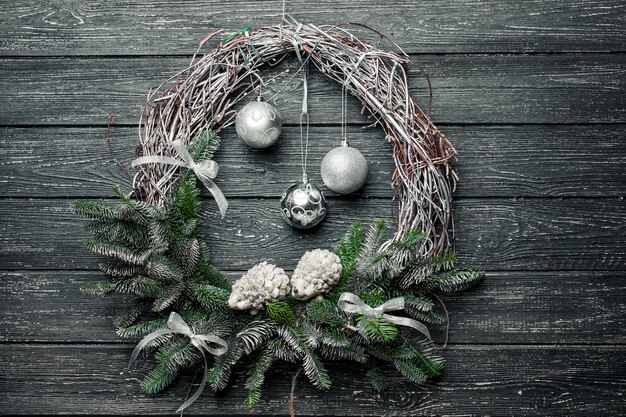 Christmas wreath with ornaments on black wooden background