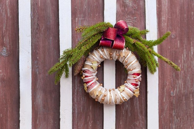 Christmas wreath on wooden door fastened in ring and used for decoration with red bow