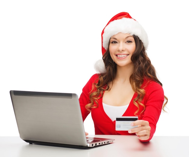 christmas, x-mas, online shopping concept - woman in santa helper hat with laptop computer and credit card