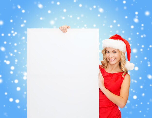 christmas, x-mas, people, advertisement, sale concept - happy woman in santa helper hat with blank white board