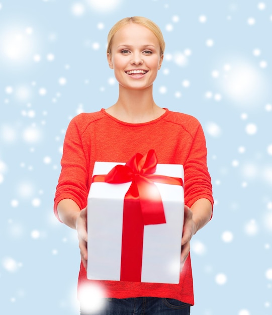 christmas, x-mas, valentine's day, celebration concept - smiling woman in red sweater with gift box