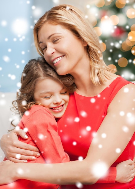 christmas, x-mas, winter, happiness concept - hugging mother and daughter