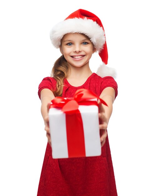 christmas, x-mas, winter, happiness concept - smiling girl in santa helper hat with gift box