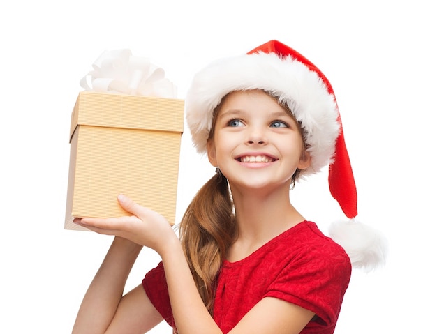 christmas, x-mas, winter, happiness concept - smiling girl in santa helper hat with gift box