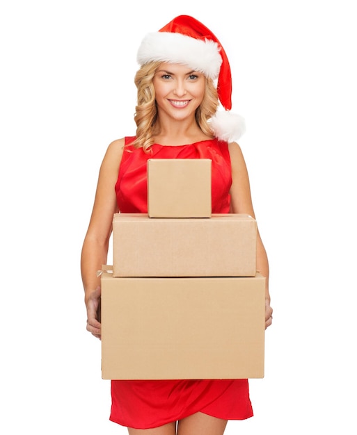 christmas, x-mas, winter, happiness concept - smiling woman in santa helper hat with many parcel boxes