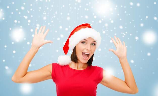 christmas, x-mas, winter, happiness concept - surprised woman in santa helper hat