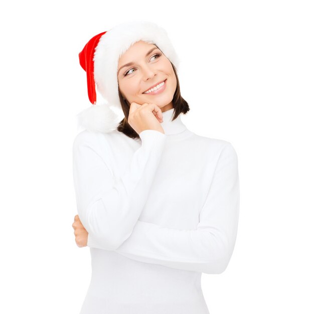 christmas, x-mas, winter, happiness concept - thinking and smiling woman in santa helper hat